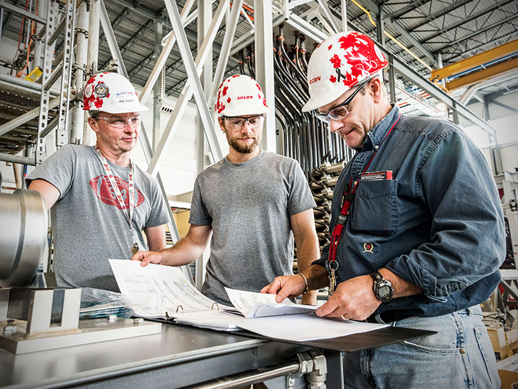 Three men looking at construction plans wearing hardhats