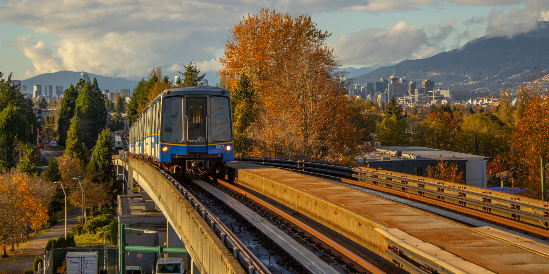 Vancouver Skytrain on train tracks with mountains and trees in the distance